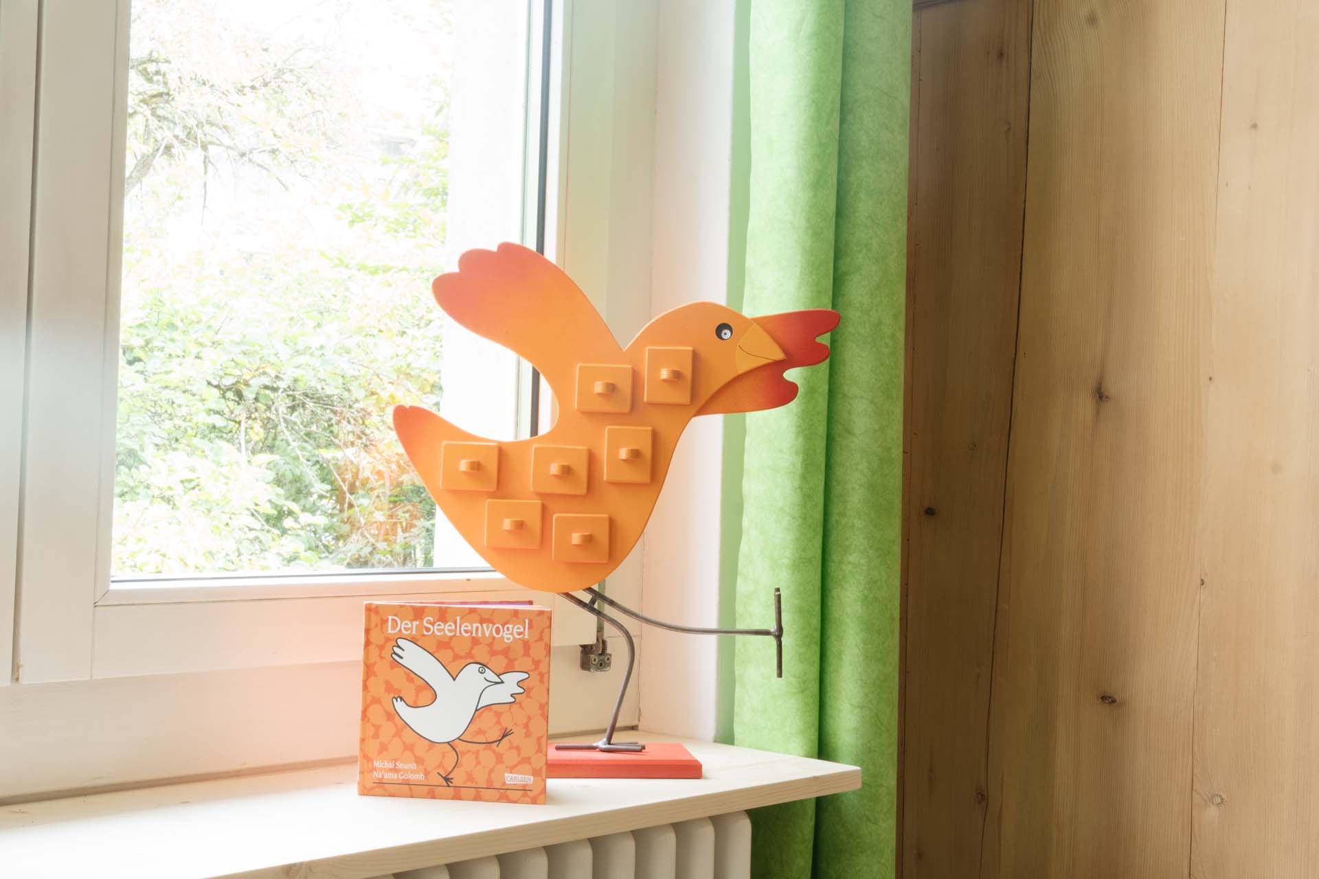 Oranger Holz-Vogel mit dem Buch Der Seelenvogel.