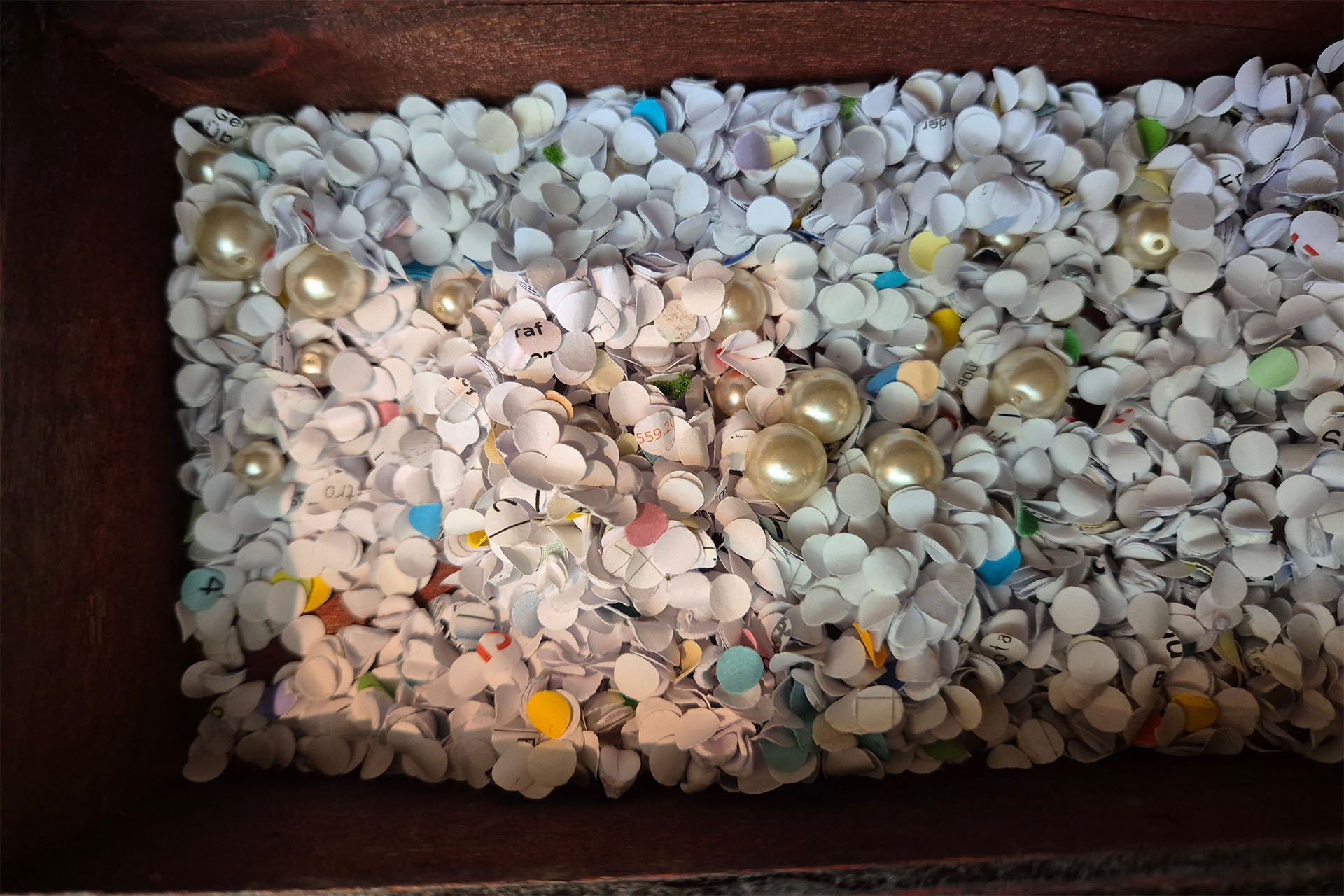 Papierschnipsel mit Perlen drin.