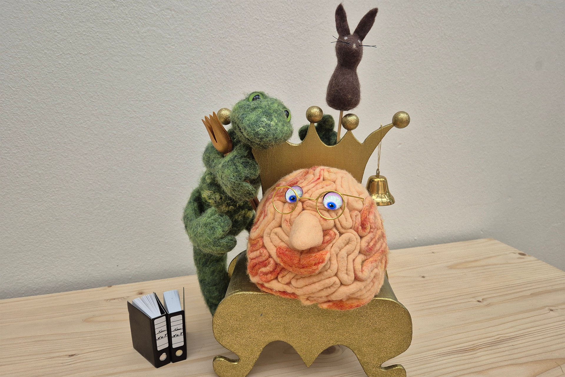 Filz-Hirn auf goldenem Stuhl mit Filz-Kröte und Filz-Hase,
